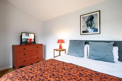 a bedroom with a bed with blue pillows and a dresser at Oak Barn - Sleeps 3, Sweffling, near #Sizewell #Aldeburgh #Saxmundham - Managed by Aldeburgh Coastal Cottages in Rendham