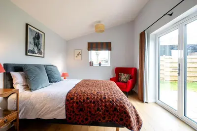 a bedroom with a bed and a red chair at Oak Barn - Sleeps 3, Sweffling, near #Sizewell #Aldeburgh #Saxmundham - Managed by Aldeburgh Coastal Cottages in Rendham
