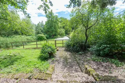 a garden with a fence and a path at Gardeners Cottage by Group Retreats in Hadleigh