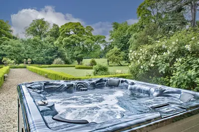 a hot tub in the middle of a garden at Gardeners Cottage by Group Retreats in Hadleigh