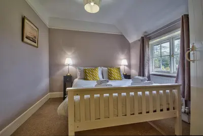 a bedroom with a bed with yellow pillows and a window at Gardeners Cottage by Group Retreats in Hadleigh