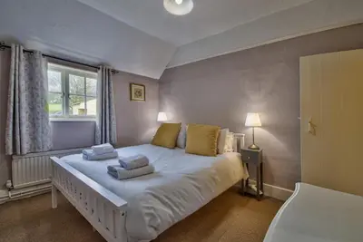 a bedroom with a large white bed with yellow pillows at Gardeners Cottage by Group Retreats in Hadleigh