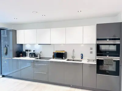 a large kitchen with white cabinets and appliances at Bright Corner Apartment by Cambridge Station with Free Allocated Underground Parking & Flexible Beds in Cambridge