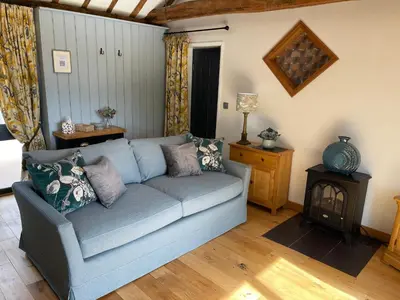 a living room with a blue couch and a table at The Tack Room at Green Farm Lodge in Stowmarket