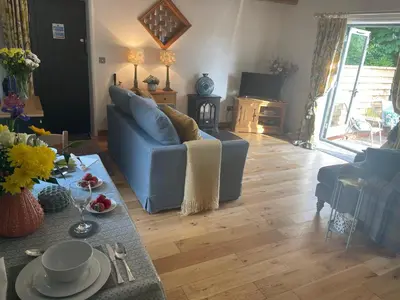 a living room with a blue couch and a wooden floor at The Tack Room at Green Farm Lodge in Stowmarket