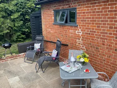 a patio with a table and chairs and a brick wall at The Tack Room at Green Farm Lodge in Stowmarket