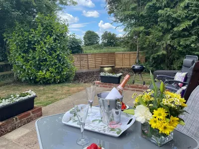 a table with wine glasses and flowers on a patio at The Tack Room at Green Farm Lodge in Stowmarket