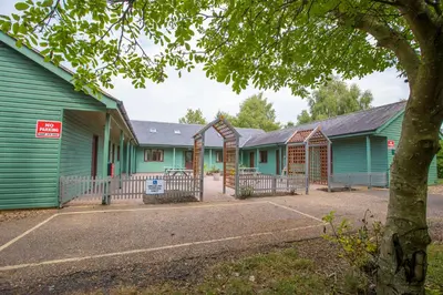 a row of green buildings with a tree at Lakeside Lodge Golf and Country Club in Huntingdon
