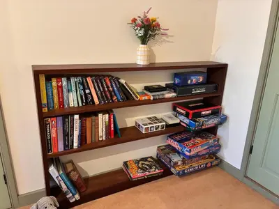 a book shelf filled with lots of books at Dog-friendly rural retreat in Bury Saint Edmunds