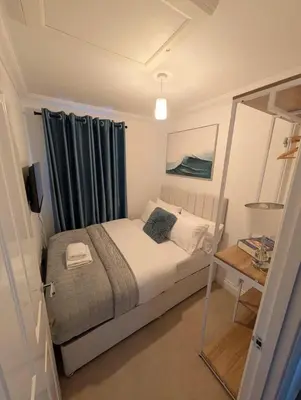 a small bedroom with a bed with blue curtains at Modern 3BR House I Garden I Cambridge I Parking x 2