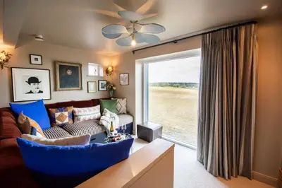 a living room with a couch and a large window at The Barn at Manor Farm in Great Glemham