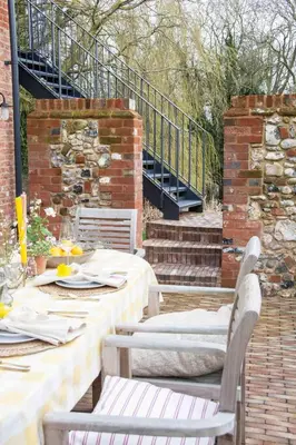 a patio with a table and chairs and a staircase at The Barn at Manor Farm in Great Glemham