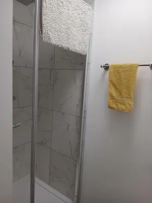 a shower with a glass door and a towel at Great En-suite room, room 4 in Ipswich