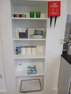 a white pantry with plates and dishes on shelves at Great En-suite room, room 4 in Ipswich