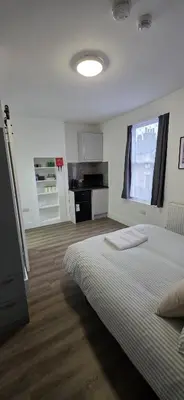 a white bedroom with a bed and a kitchen at Great En-suite room, room 4 in Ipswich