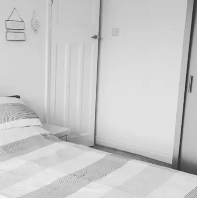 a white bedroom with a bed and a door at Walton holiday home in Walton-on-the-Naze