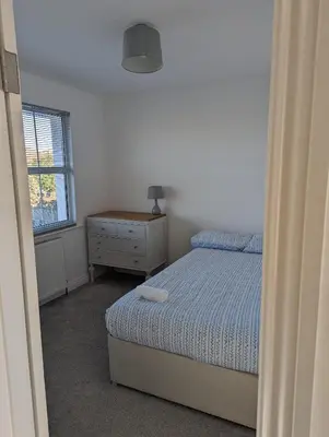 a bedroom with a bed and a dresser and a window at Walton holiday home in Walton-on-the-Naze