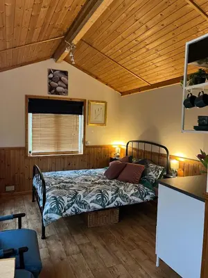 a bedroom with a bed in a room with wooden ceilings at Readers Cabin-Cosy Countryside Studio Cabin in Great Sampford