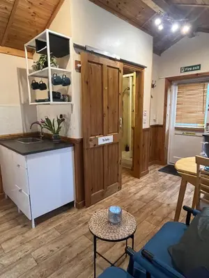 a living room with a kitchen and a table at Readers Cabin-Cosy Countryside Studio Cabin in Great Sampford