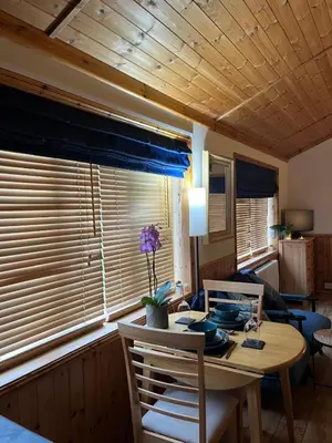 a dining room with a table and chairs and a window at Readers Cabin-Cosy Countryside Studio Cabin in Great Sampford