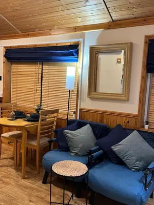 a living room with a blue couch and a table at Readers Cabin-Cosy Countryside Studio Cabin in Great Sampford