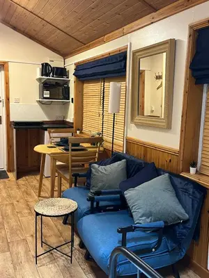 a living room with a blue couch and a table at Readers Cabin-Cosy Countryside Studio Cabin in Great Sampford