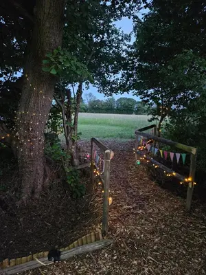 a park with a tree and a fence with lights at Readers Cabin-Cosy Countryside Studio Cabin in Great Sampford