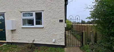a white house with a window and a fence at Comfy 1 bed in the idyllic village of Hemingford Grey in Hemingford Grey