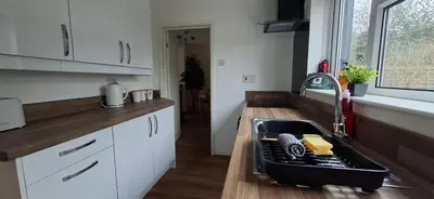 a kitchen with white cabinets and a sink with a dishwasher at Comfy 1 bed in the idyllic village of Hemingford Grey in Hemingford Grey