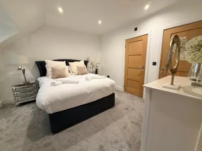 a bedroom with a large bed and a mirror at Turnpike Red Lodge in Bury Saint Edmunds