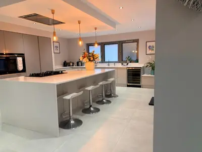 a kitchen with a large island with bar stools at Turnpike Red Lodge in Bury Saint Edmunds
