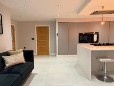a living room with a couch and a kitchen at Turnpike Red Lodge in Bury Saint Edmunds