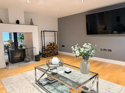 a living room with a glass table and a vase of flowers at Turnpike Red Lodge in Bury Saint Edmunds
