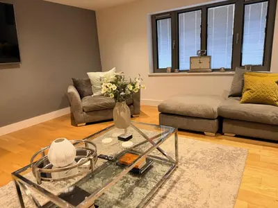 a living room with a glass table and a couch at Turnpike Red Lodge in Bury Saint Edmunds