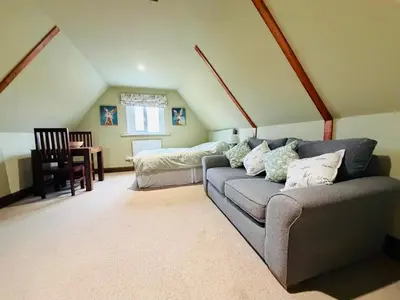 a living room with a couch and a bed at The Barn at Catley Cross House in Little Maplestead