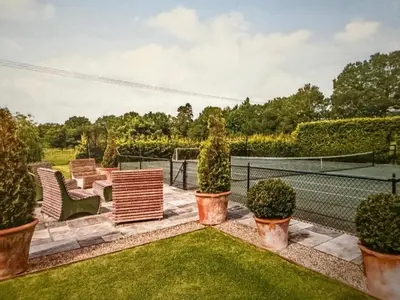 a tennis court with chairs and a tennis racket at The Barn at Catley Cross House in Little Maplestead