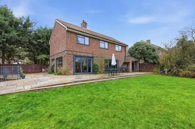 a brick house with a patio and a lawn at Luxury 5 Bedroom with Pool & Games Room in Potter Street