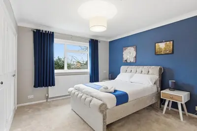 a bedroom with a bed with blue walls and a window at Luxury 5 Bedroom with Pool & Games Room in Potter Street