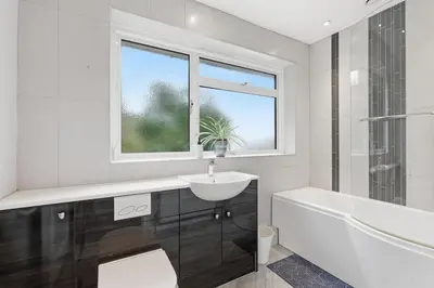 a white bathroom with a sink and a tub and a window at Luxury 5 Bedroom with Pool & Games Room in Potter Street