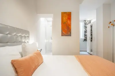 a white bedroom with a large white bed and a painting at Apartment Clarke in Cambridge