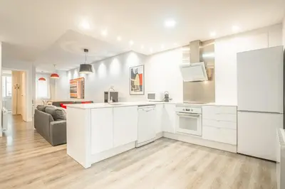 a kitchen with white cabinets and a living room at Apartment Clarke in Cambridge