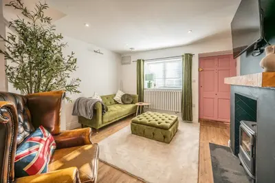 a living room with a couch and a fireplace at Pink Cottage, Leiston in Leiston