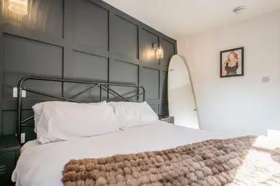 a bedroom with a bed with a black wall and a surfboard at Pink Cottage, Leiston in Leiston