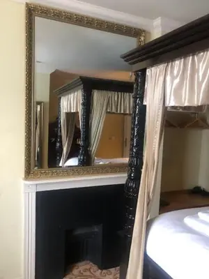 a mirror over a fireplace in a bedroom at Colchester Boutique Hotel in Colchester