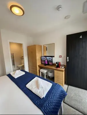 a bedroom with a bed and a desk with a computer at The Jolly Brewers in Bishops Stortford