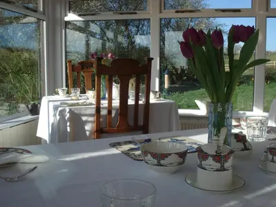 a table with purple tulips in a vase on it at Oak Tree Farm in Yoxford