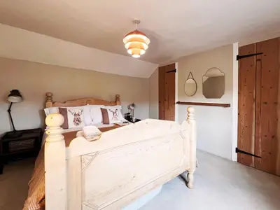 a bedroom with a wooden bed in a room at Columbine Cottage by The Suffolk Cottage Collection in Middleton