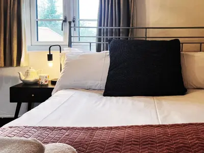 a bed with a black pillow on top of it at Columbine Cottage by The Suffolk Cottage Collection in Middleton