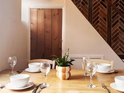 a wooden table with plates and glasses on it at Columbine Cottage by The Suffolk Cottage Collection in Middleton