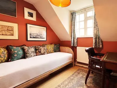 a bedroom with orange walls and a bed with a window at Peak Hill Cottage in Theberton